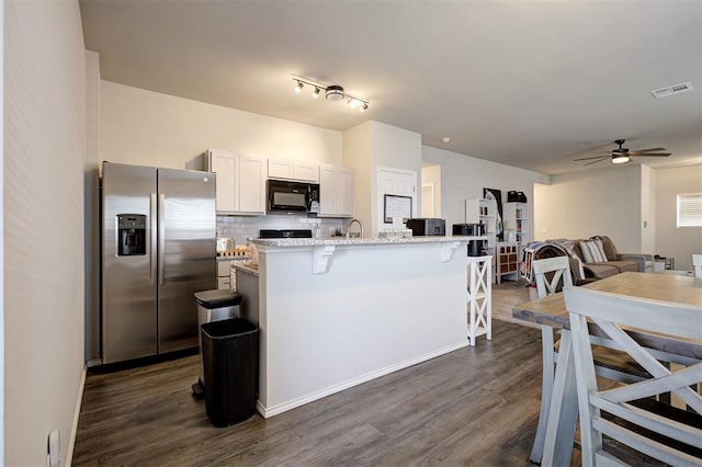 11725 Casey Dr, Yukon, OK 73099 - kitchen with stainless steel fridge, black microwave, a kitchen breakfast bar, ceiling fan, and dark wood finished floors