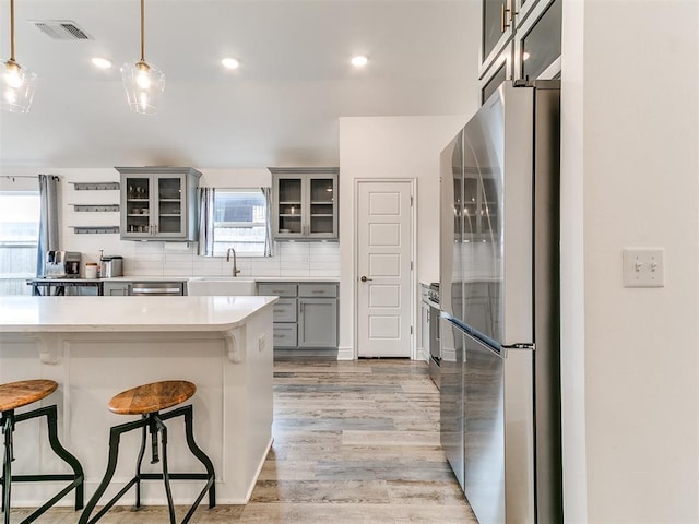6516 SE 87th St, Oklahoma City, OK 73135 - kitchen with stainless steel appliances, gray cabinetry, a breakfast bar, light wood-style floors, and plenty of natural light
