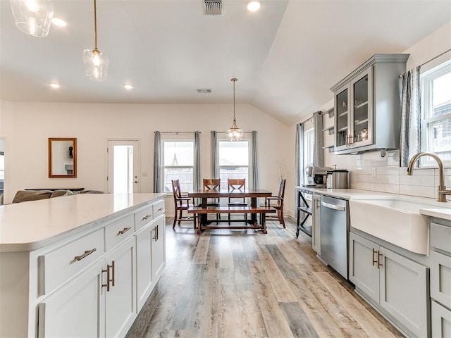 6516 SE 87th St, Oklahoma City, OK 73135 - kitchen featuring stainless steel dishwasher, light countertops, lofted ceiling, glass insert cabinets, and gray cabinetry
