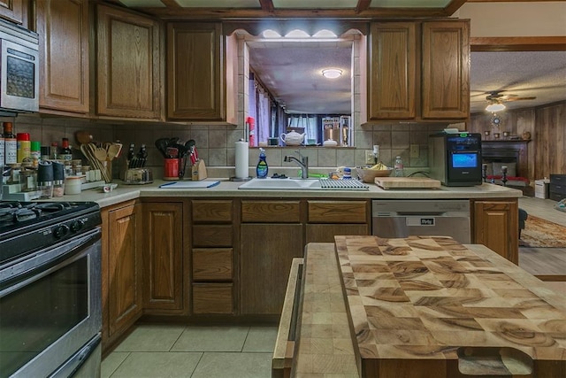 2317 N Redmond Ave, Bethany, OK 73008 - kitchen featuring appliances with stainless steel finishes, backsplash, light tile patterned floors, and brown cabinets
