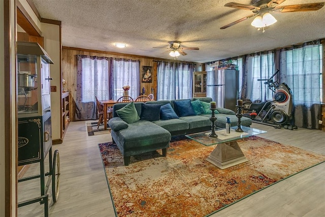 2317 N Redmond Ave, Bethany, OK 73008 - living room featuring a textured ceiling, ceiling fan, light wood-style floors, and wood walls