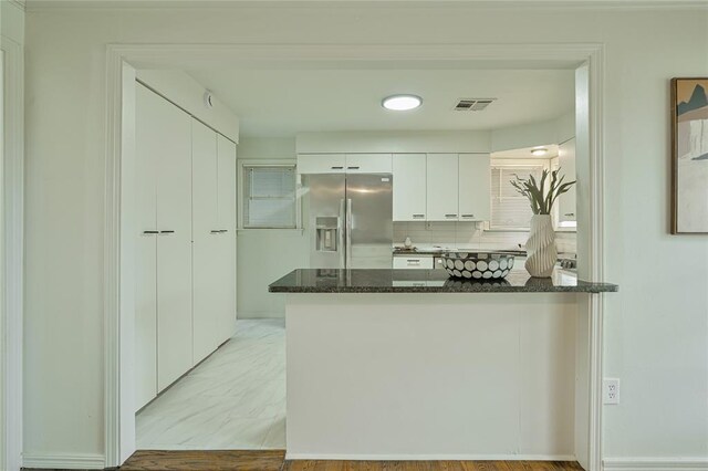 1200 NW 95th St, Oklahoma City, OK 73114 - kitchen with stainless steel fridge with ice dispenser, white cabinets, dark stone countertops, a peninsula, and decorative backsplash