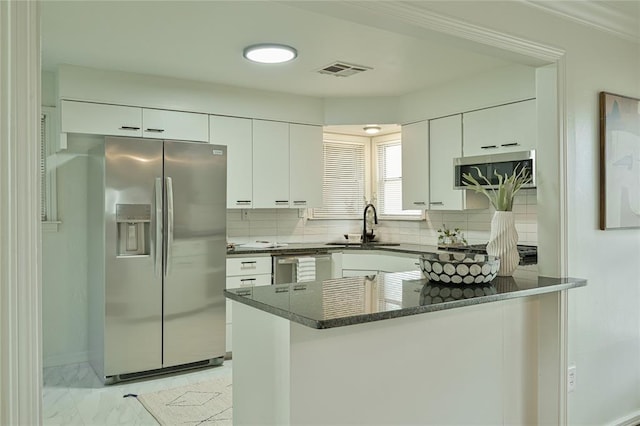 1200 NW 95th St, Oklahoma City, OK 73114 - kitchen featuring appliances with stainless steel finishes, a peninsula, tasteful backsplash, and white cabinets
