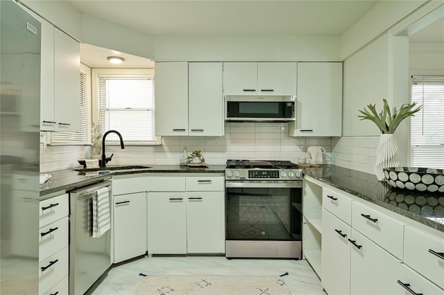 1200 NW 95th St, Oklahoma City, OK 73114 - kitchen featuring appliances with stainless steel finishes, light marble finish flooring, decorative backsplash, and plenty of natural light