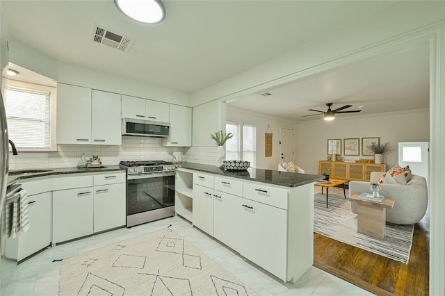 1200 NW 95th St, Oklahoma City, OK 73114 - kitchen featuring appliances with stainless steel finishes, a peninsula, decorative backsplash, white cabinets, and ceiling fan