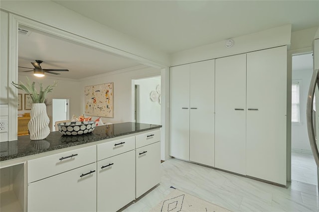 1200 NW 95th St, Oklahoma City, OK 73114 - kitchen with dark stone countertops, a ceiling fan, white cabinetry, ornamental molding, and light marble finish floors