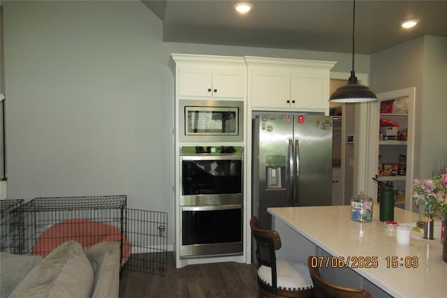 3909 Sorano Dr, Moore, OK 73160 - kitchen with appliances with stainless steel finishes, white cabinets, dark wood finished floors, light countertops, and a kitchen breakfast bar