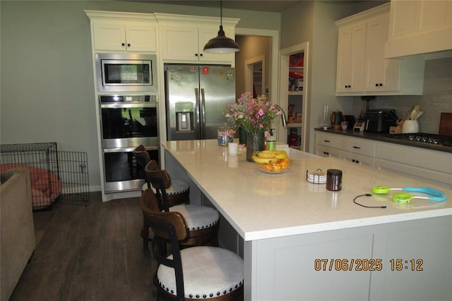 3909 Sorano Dr, Moore, OK 73160 - kitchen with appliances with stainless steel finishes, white cabinets, dark wood-style floors, decorative light fixtures, and backsplash