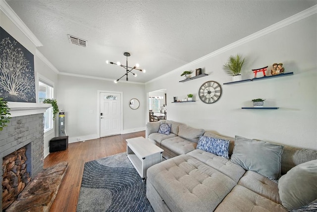 1530 NW 32nd St, Oklahoma City, OK 73118 - living room featuring a chandelier, wood finished floors, crown molding, a textured ceiling, and a brick fireplace
