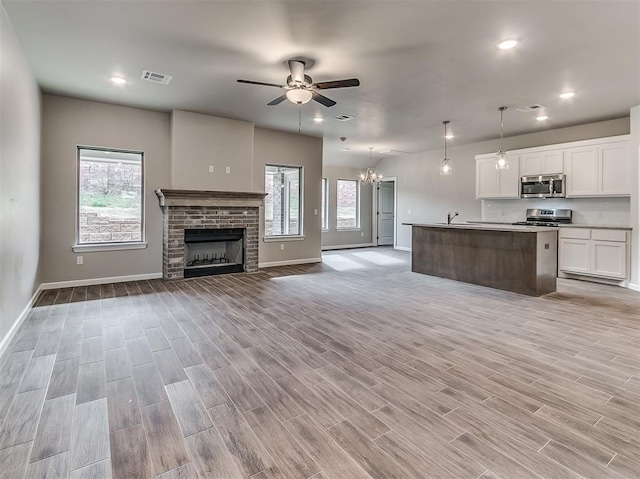 600 Mirano Ln, Edmond, OK 73034 - kitchen featuring appliances with stainless steel finishes, open floor plan, ceiling fan, white cabinets, and a chandelier