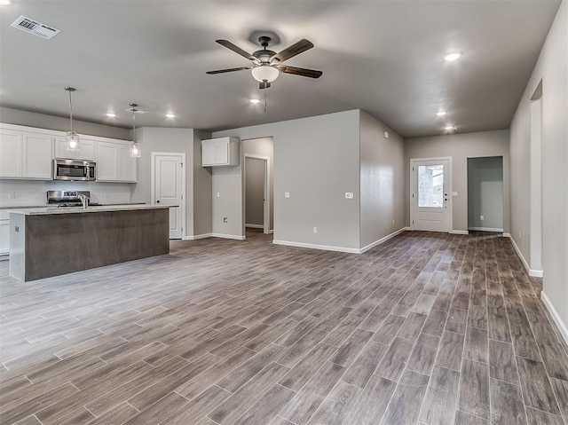 600 Mirano Ln, Edmond, OK 73034 - kitchen with stainless steel appliances, open floor plan, light wood finished floors, white cabinetry, and recessed lighting