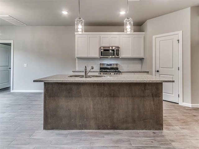 600 Mirano Ln, Edmond, OK 73034 - kitchen featuring appliances with stainless steel finishes, light stone counters, tasteful backsplash, a center island with sink, and recessed lighting
