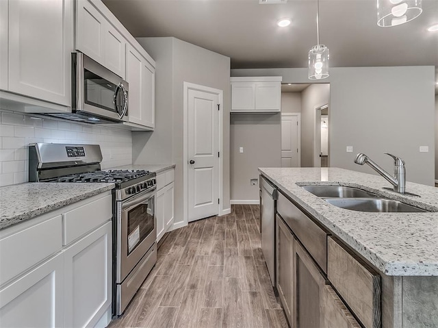 600 Mirano Ln, Edmond, OK 73034 - kitchen with stainless steel appliances, white cabinets, light wood-style floors, decorative backsplash, and pendant lighting