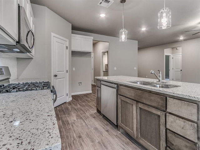 600 Mirano Ln, Edmond, OK 73034 - kitchen with appliances with stainless steel finishes, light stone countertops, decorative light fixtures, wood finished floors, and white cabinets