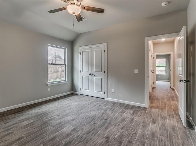 600 Mirano Ln, Edmond, OK 73034 - unfurnished bedroom with dark wood finished floors, vaulted ceiling, a closet, and a ceiling fan