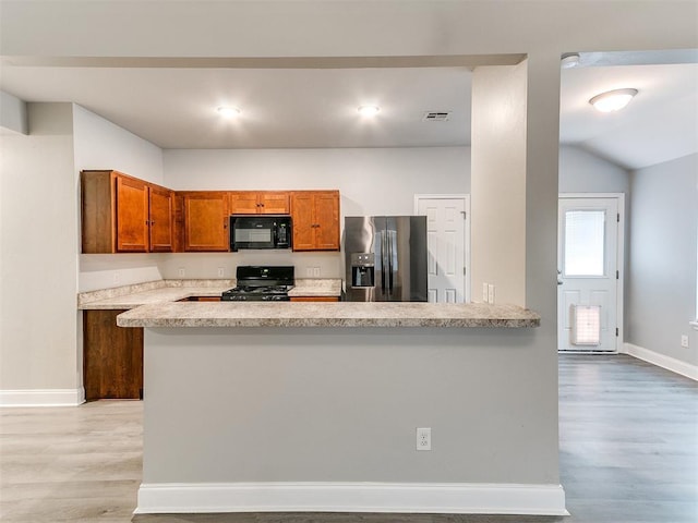 11104 NW 99th St, Yukon, OK 73099 - kitchen with fridge with ice dispenser, black microwave, stove, light wood finished floors, and brown cabinetry