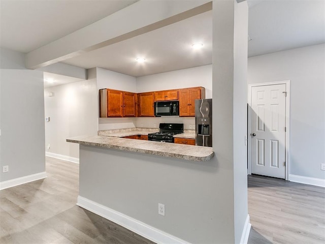11104 NW 99th St, Yukon, OK 73099 - kitchen featuring black appliances, light countertops, light wood-style floors, brown cabinetry, and a peninsula