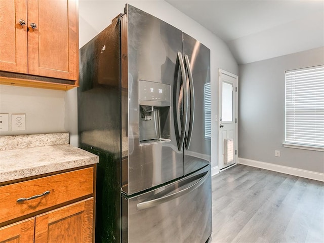 11104 NW 99th St, Yukon, OK 73099 - kitchen with stainless steel fridge with ice dispenser, vaulted ceiling, wood finished floors, light countertops, and brown cabinets