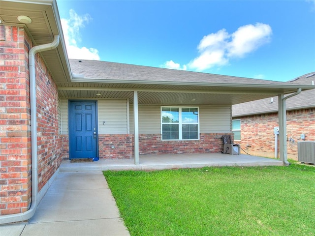 11104 NW 99th St, Yukon, OK 73099 - property entrance featuring brick siding, a shingled roof, a yard, and a porch
