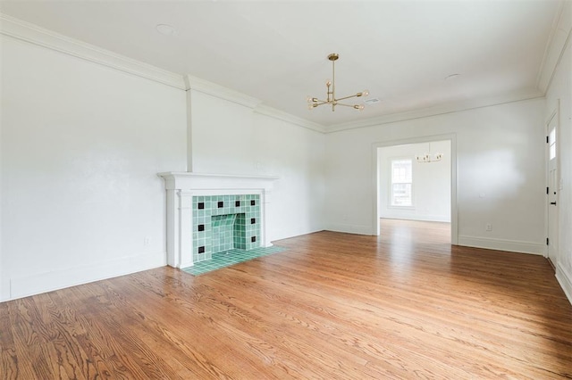 826 NE 18th St, Oklahoma City, OK 73105 - unfurnished living room featuring a chandelier, crown molding, light wood finished floors, and a tile fireplace