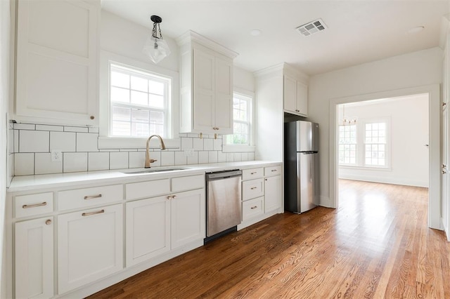 826 NE 18th St, Oklahoma City, OK 73105 - kitchen with appliances with stainless steel finishes, decorative backsplash, white cabinetry, wood finished floors, and light countertops