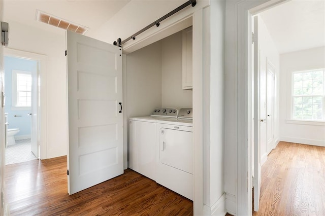 826 NE 18th St, Oklahoma City, OK 73105 - washroom featuring cabinet space, washing machine and clothes dryer, a barn door, and wood finished floors