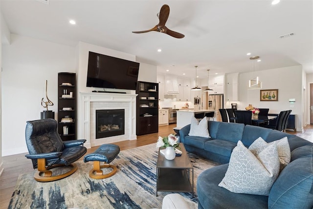 209 Pont Neuf Ct, Edmond, OK 73034 - living room with light wood finished floors, ceiling fan, recessed lighting, and a glass covered fireplace