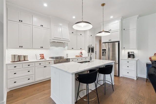 209 Pont Neuf Ct, Edmond, OK 73034 - kitchen with appliances with stainless steel finishes, light wood-type flooring, backsplash, white cabinets, and a breakfast bar