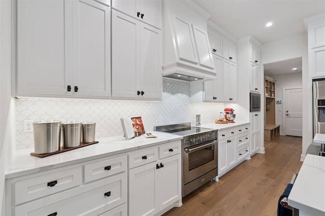 209 Pont Neuf Ct, Edmond, OK 73034 - kitchen featuring stainless steel appliances, premium range hood, white cabinets, wood finished floors, and decorative backsplash