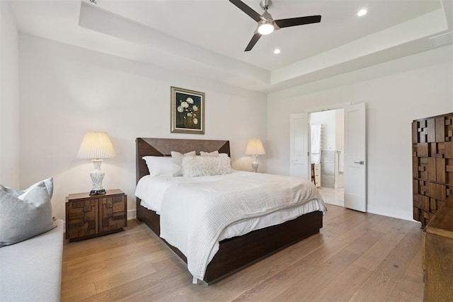 209 Pont Neuf Ct, Edmond, OK 73034 - bedroom featuring light wood finished floors, a tray ceiling, recessed lighting, ensuite bathroom, and ceiling fan
