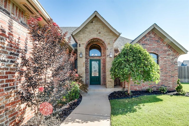 10812 Wild Horse Creek Dr, Yukon, OK 73099 - doorway to property featuring brick siding, a yard, a shingled roof, and stone siding