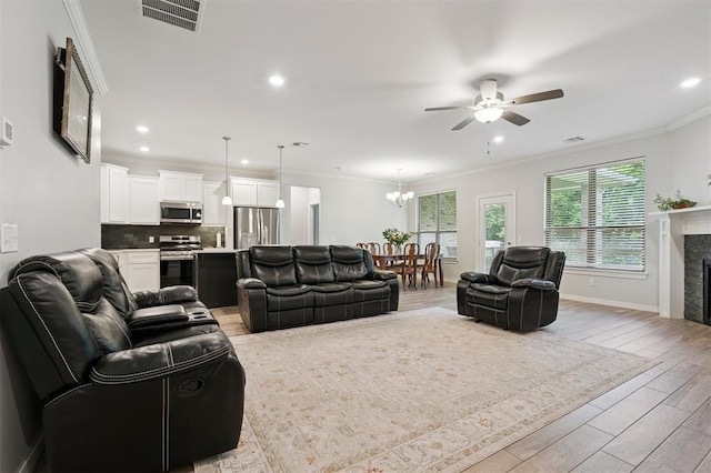 1512 N Kamryn Way, Mustang, OK 73064 - living room featuring a ceiling fan, light wood finished floors, a fireplace, recessed lighting, and crown molding