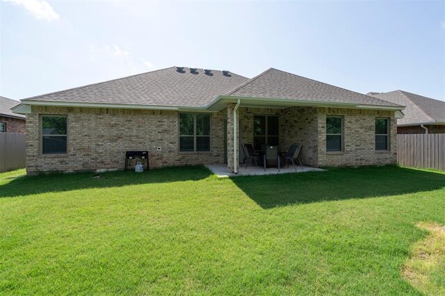 1512 N Kamryn Way, Mustang, OK 73064 - back of property featuring a shingled roof, a fenced backyard, a patio, and brick siding
