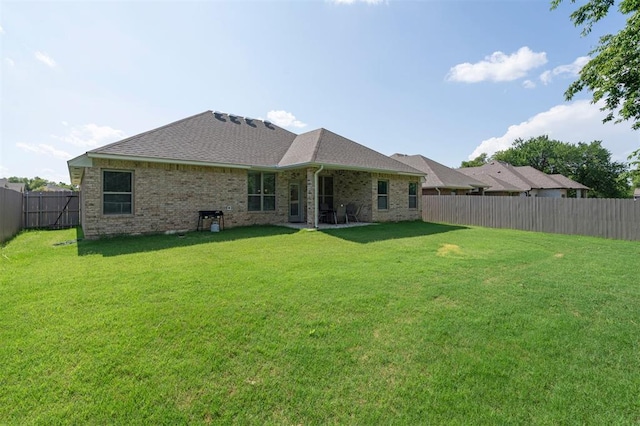 1512 N Kamryn Way, Mustang, OK 73064 - rear view of house featuring a fenced backyard, brick siding, and a shingled roof
