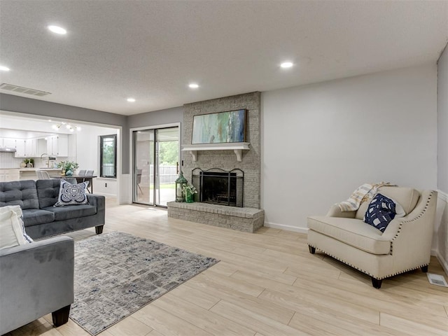 5412 Cloverlawn Dr, Oklahoma City, OK 73135 - living room with light wood-type flooring, recessed lighting, a brick fireplace, and a textured ceiling