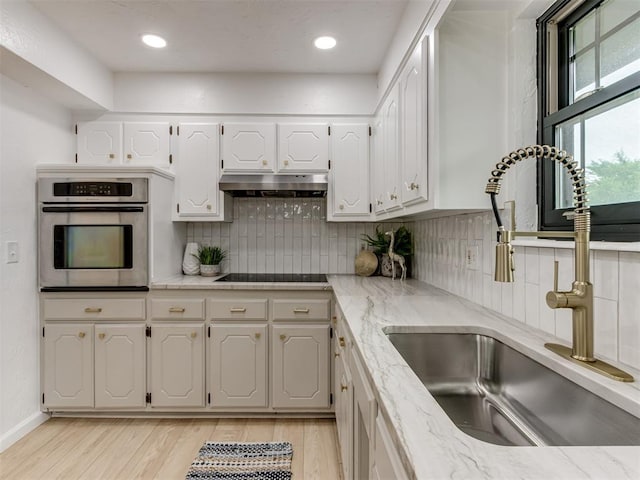 5412 Cloverlawn Dr, Oklahoma City, OK 73135 - kitchen with oven, under cabinet range hood, light wood-style floors, white cabinetry, and recessed lighting