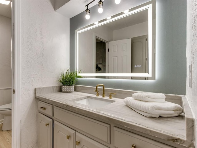 5412 Cloverlawn Dr, Oklahoma City, OK 73135 - bathroom featuring vanity, a textured wall, and wood finished floors