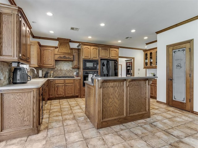 559 Silver Tree Cir, Choctaw, OK 73020 - kitchen with black appliances, crown molding, premium range hood, tasteful backsplash, and brown cabinetry