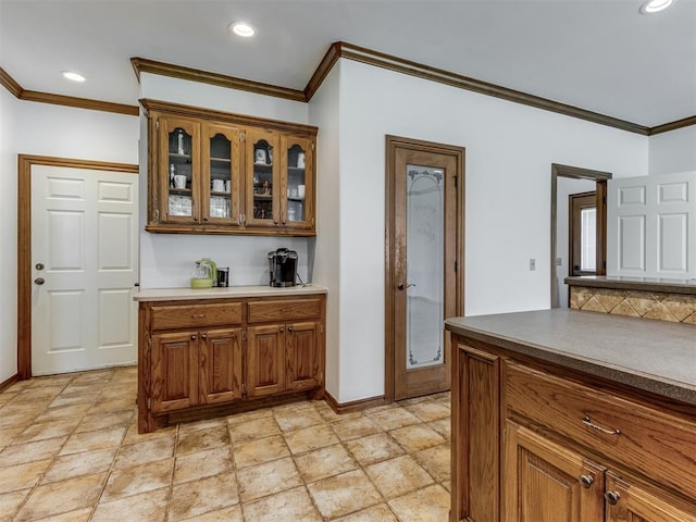 559 Silver Tree Cir, Choctaw, OK 73020 - kitchen featuring crown molding, brown cabinets, glass insert cabinets, recessed lighting, and light stone finish floors