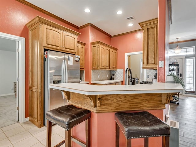 1801 Wagon Trail Blvd, Harrah, OK 73045 - kitchen with stainless steel fridge, ornamental molding, a kitchen breakfast bar, light countertops, and decorative backsplash