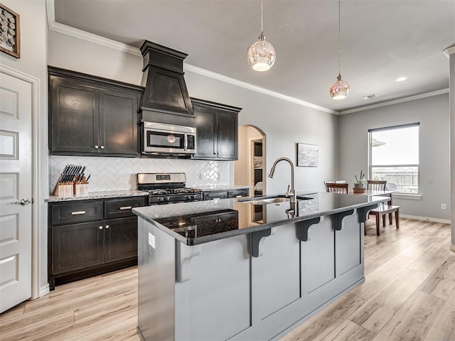 10824 NW 32nd Ter, Yukon, OK 73099 - kitchen with appliances with stainless steel finishes, arched walkways, a breakfast bar, crown molding, and a center island with sink