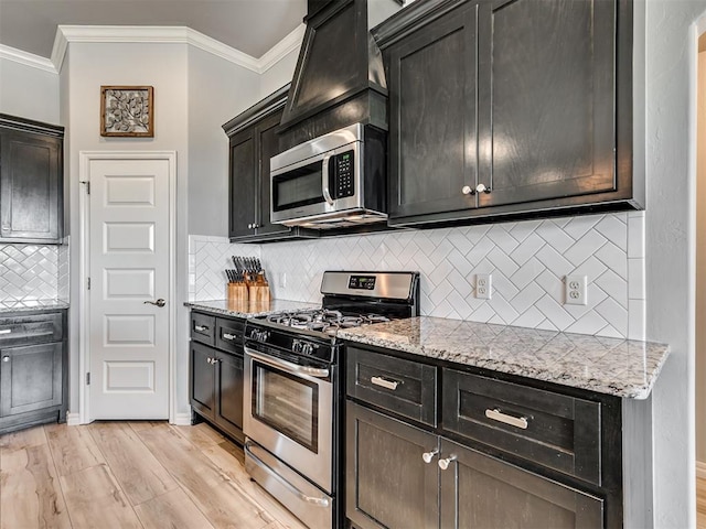 10824 NW 32nd Ter, Yukon, OK 73099 - kitchen featuring appliances with stainless steel finishes, crown molding, tasteful backsplash, light stone counters, and light wood-style floors