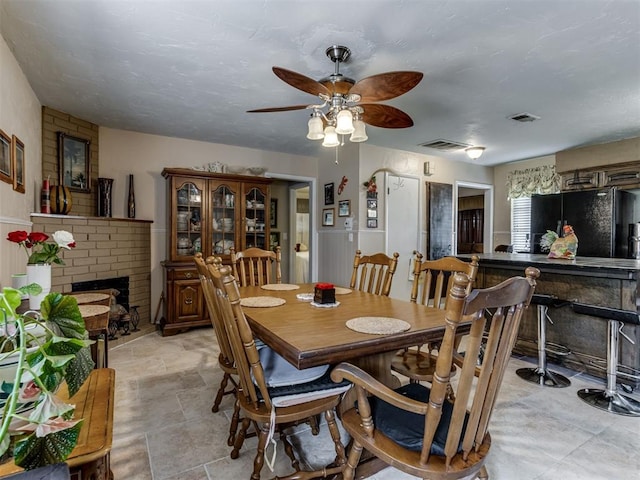 1200 Kingston Dr, Yukon, OK 73099 - dining room featuring a fireplace, a ceiling fan, and light stone finish flooring