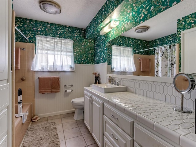 1200 Kingston Dr, Yukon, OK 73099 - bathroom featuring wallpapered walls, a wainscoted wall, a textured ceiling, shower / bath combo, and vanity