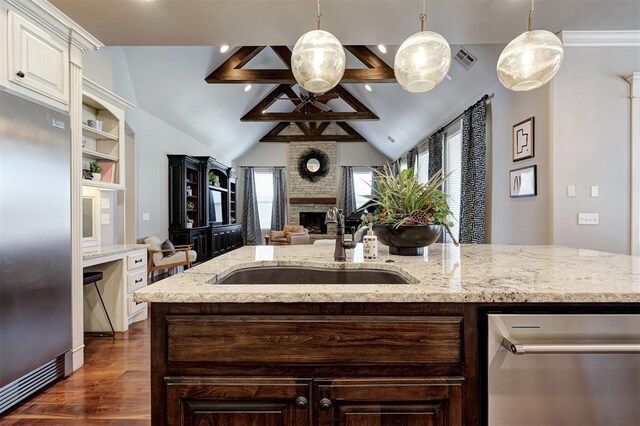 4409 Farm Hill Rd, Norman, OK 73072 - kitchen featuring appliances with stainless steel finishes, dark wood finished floors, open floor plan, a large fireplace, and light stone countertops