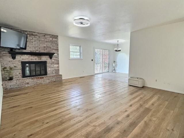 1024 E 12th St, Cushing, OK 74023 - unfurnished living room featuring wood finished floors, a fireplace, and a chandelier