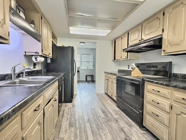 1024 E 12th St, Cushing, OK 74023 - kitchen featuring black electric range oven, under cabinet range hood, light wood-style flooring, dark countertops, and dishwashing machine