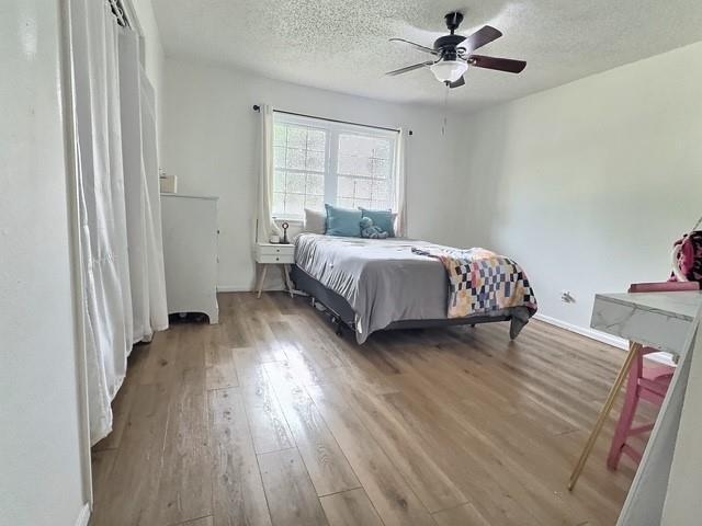 1024 E 12th St, Cushing, OK 74023 - bedroom with wood finished floors, a textured ceiling, and a ceiling fan