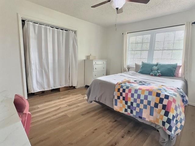 1024 E 12th St, Cushing, OK 74023 - bedroom with a textured ceiling, wood finished floors, and a ceiling fan