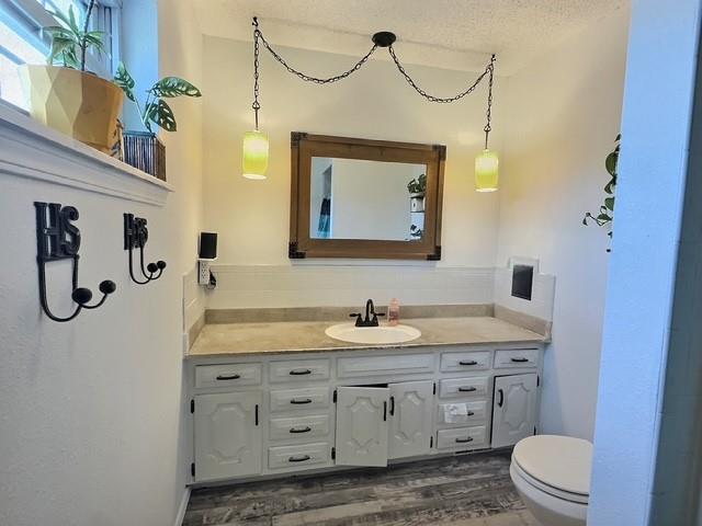 1024 E 12th St, Cushing, OK 74023 - bathroom with vanity, wood finished floors, and a textured ceiling